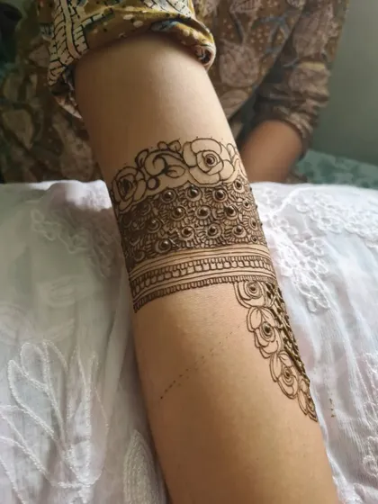A close-up of a bridal armband featuring beautiful rose motifs and peacock-inspired patterns.