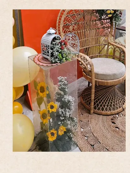 A detail shot of the decor, including a clear acrylic plinth filled with sunflowers, adding a modern and floral touch to the boho-chic theme.