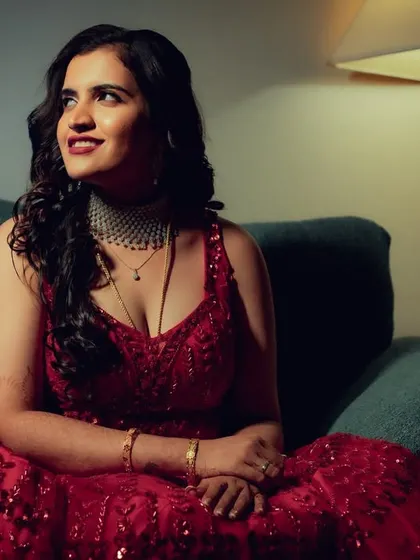 An indoor portrait of a woman in a beautiful red gown, bathed in soft, moody lighting. The mix of cool and warm tones adds a modern, cinematic feel to the shot.