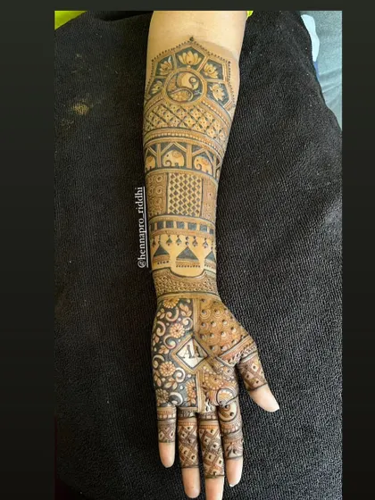A super intricate single-hand design. This showcases how many attractive elements like peacocks, elephants, and geometric fills can be woven into one cohesive and stunning piece.