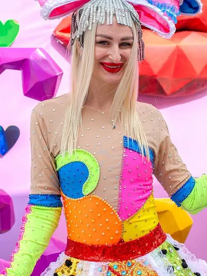 A close-up of a performer in a whimsical, colorful costume, complete with a giant bow and heart-shaped glasses. These entertainers are a key part of creating an immersive carnival experience.