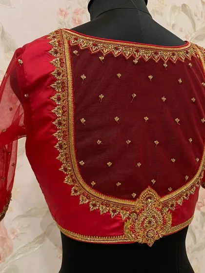 The full back view of the red net blouse, highlighting the intricate embroidery and central motif.