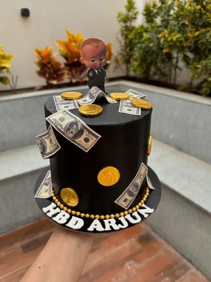 A different take on the Boss Baby theme, this tall black cake is decorated with edible money and gold coins for a fun, money-heist vibe.