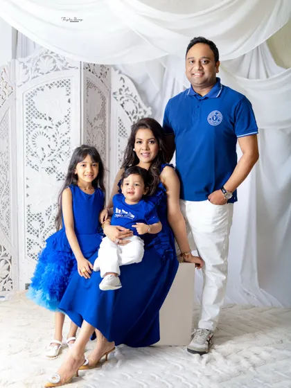 A happy family of four, coordinated in royal blue and white. This classic portrait against a simple white backdrop is timeless and elegant.