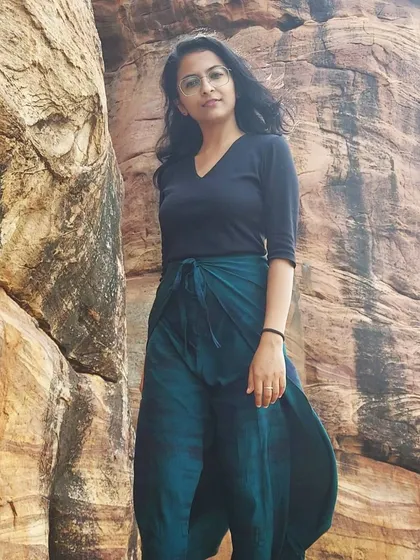 An explorer-style shot against the ancient rock formations of Badami. This image captures a sense of history and adventure, perfect for travel storytelling.