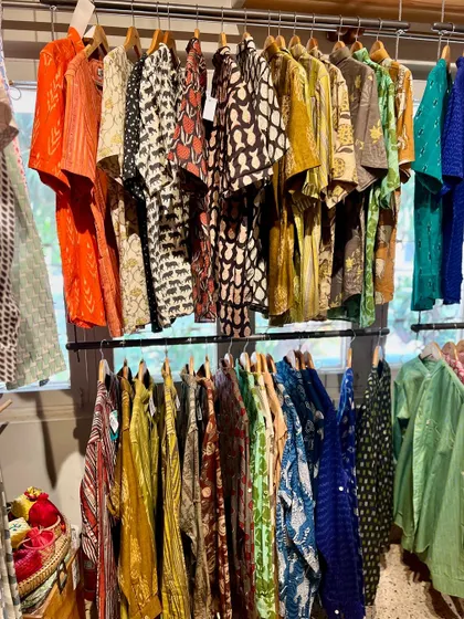 A happy customer browsing our apparel section, filled with colorful hand-block printed shirts and kurtas. Our stores are designed to be a treasure trove where you can find unique, ethically sourced pieces for the whole family.
