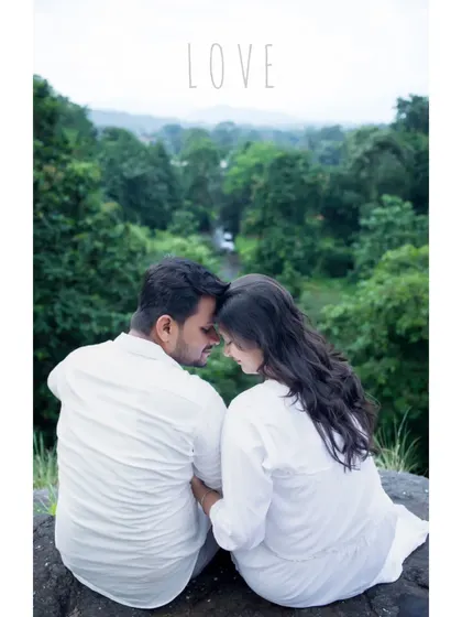 An intimate and romantic maternity portrait of a couple dressed in white, sitting together overlooking a lush green valley. This quiet moment, with their foreheads touching, beautifully captures the love and serenity of their journey together.