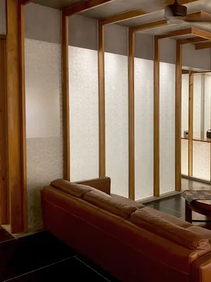 This perspective shows how the series of wood-framed 'lantern' partitions organizes the entire living space in the Lucknow penthouse. They create a visual rhythm that guides the eye and separates the open plan into distinct, functional zones.
