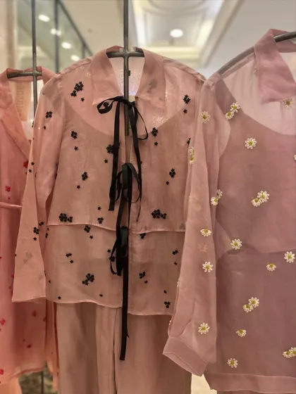 Sheer elegance stitched with floral dreams. This organza co-ord set features a delicate shirt with a black ribbon tie and scattered floral embroidery.