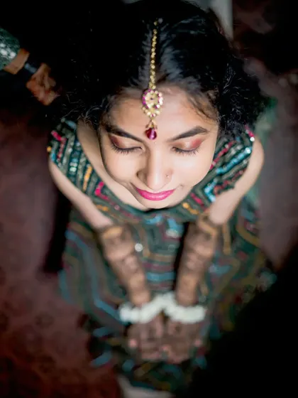 An elegant top-down shot of the bride, highlighting her makeup, maang tikka, and the beautiful henna on her hands.
