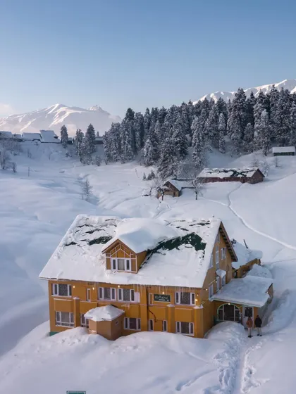 A photo of a beautiful, snow-covered hotel in Gulmarg, Kashmir, capturing the magical winter scenery of the valley.