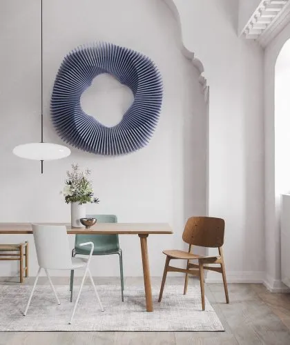 The same sculptural design in a cool blue, hung in a bright, minimalist dining area. It adds a touch of modern elegance and a pop of color.