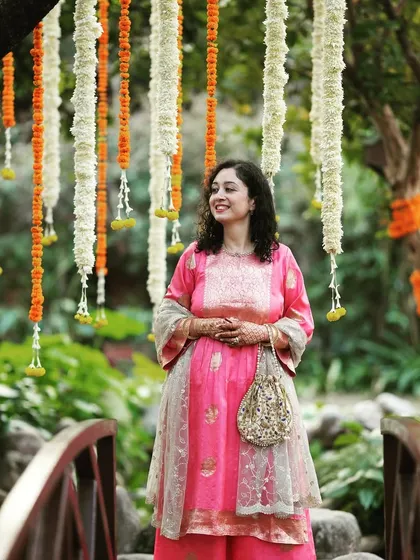 A guest poses happily against a backdrop of hanging marigold and tuberose garlands at a Mehendi function at Taj Corbett.