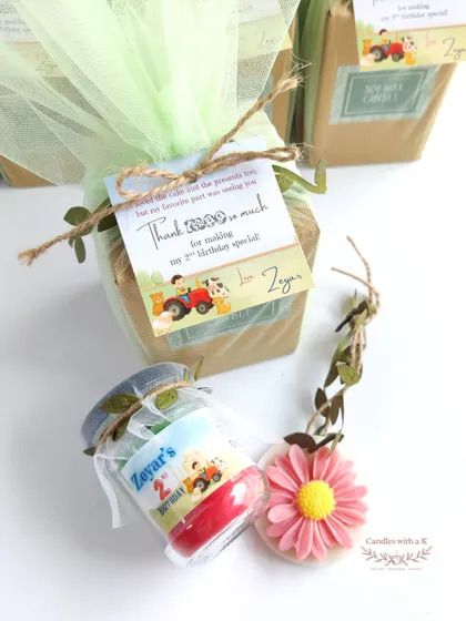 A close-up of the farm-themed gift, showing the custom thank you card, the layered candle, and the daisy sachet.