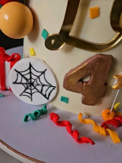 A close-up of the Spider-Man cake, showing the edible spider web emblem and the number "4" for the birthday boy.