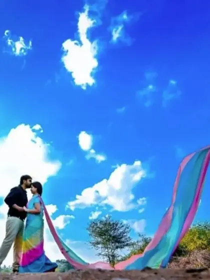 A romantic pose against a bright blue sky, with the rainbow trail adding a beautiful sweep of color.