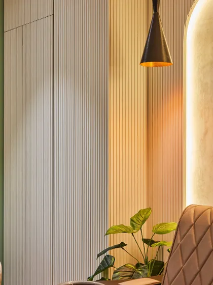A close-up of the material details within the salon. The vertical fluted panels on the cabinetry add texture and a sense of height, while the warm, focused light from the pendant lamp creates an inviting and intimate mood.