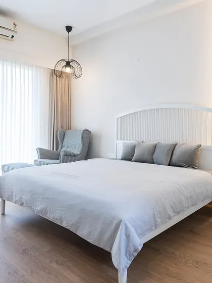 The master bedroom in the Vaswani Exquisite project, designed as a minimalist's dream with a clean white palette and functional, integrated furniture.