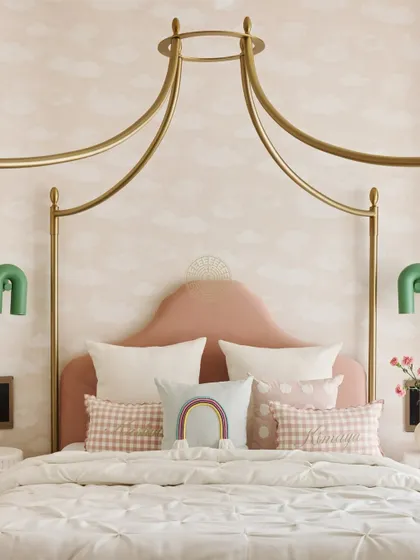 A close-up of the dreamy canopy bed with a pink velvet headboard. We layered cute pillows with rainbows and gingham patterns to add personality and fun.