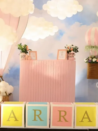 A closer view of the hot air balloon party dessert station. A teddy bear sits on the custom name blocks, and a basket with flowers hangs from a balloon.