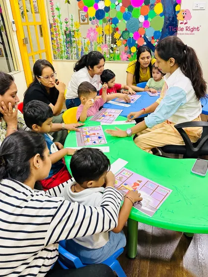 A trainer engages a group of children and parents with a photographic memory game. This activity is designed to strengthen recall, concentration, and pattern recognition in a playful setting.
