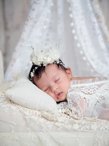 A close-up on the sleeping baby, wearing an adorable pearl and lace crown. These tiny details are what make each posed session so special.