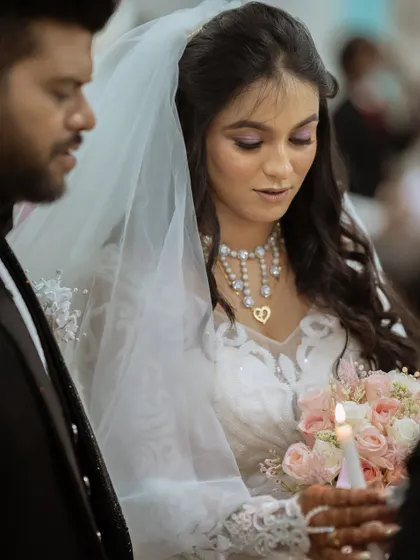 A solemn moment during the church ceremony, with the bride holding a candle.