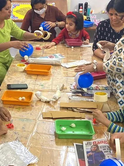 Parents and children working together during a paper mache workshop. These collaborative projects are a great way to bond and create something special as a team.
