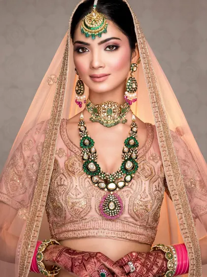 A classic bridal portrait under the veil, showcasing the soft makeup and the stunning polki jewelry set against a pastel lehenga.