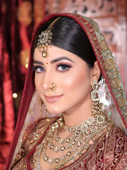 A close-up of a subtle yet stunning bridal face. The makeup features a neutral color palette with a soft brown smokey eye and a nude lip, letting the bride's natural beauty shine.