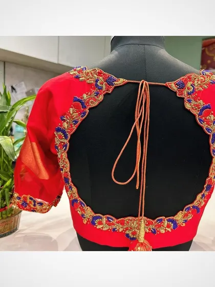 A clear view of the red blouse with the circular back cutout and handcrafted tassel. This design is perfect for festive occasions and parties.