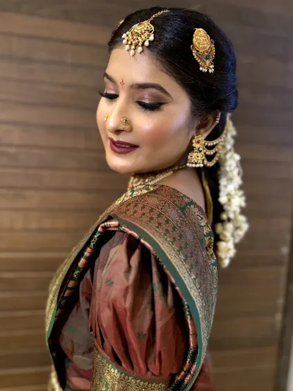 A close-up shot of this South Indian bride's look, focusing on the rich, warm tones of her makeup. The deep lipstick and defined eyes are perfectly coordinated with her silk saree and temple jewelry.