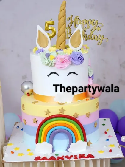 A two-tiered unicorn cake that perfectly matches the party's theme, complete with a golden horn and rainbow details.