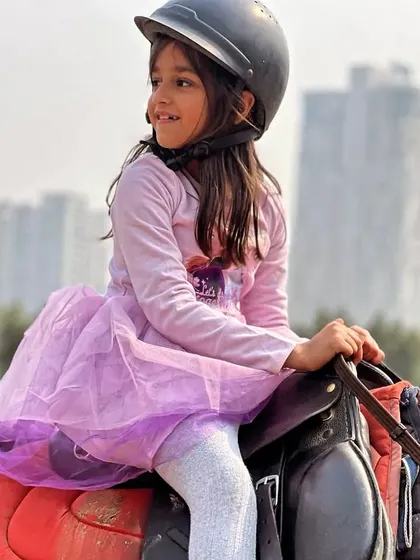 A smiling young girl enjoying her time on horseback. We aim to create a joyful and encouraging atmosphere for all our young riders.