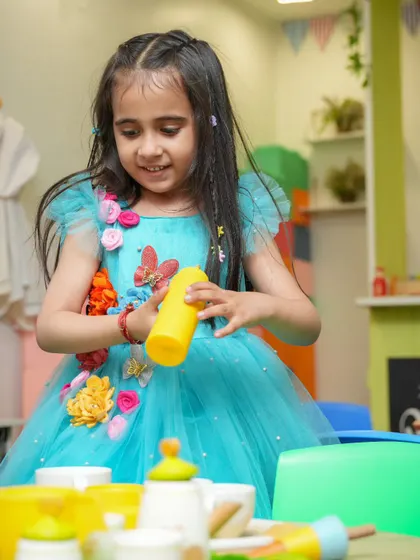 A little princess playing in our pretend-play kitchen area. This space is perfect for imaginative role-playing.