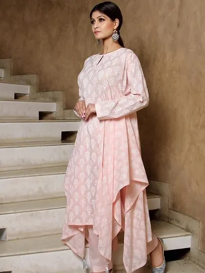 This shot showcases a modern ethnic look with a model in a pink asymmetric kurti. The unique setting on the stairs adds an editorial feel, perfect for a contemporary Indian fashion brand's lookbook.