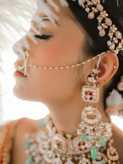 A close-up on the exquisite details. The bride's jewelry, the nath, the flawless makeup, all coming together to create a look of pure perfection.