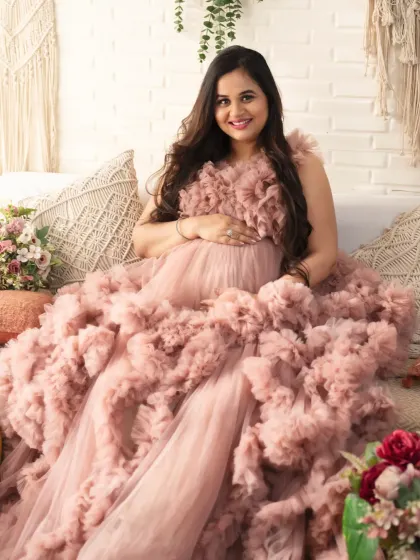 A radiant solo portrait. The mom-to-be's happy smile and the voluminous pink gown create a photo that is full of joy and celebration.