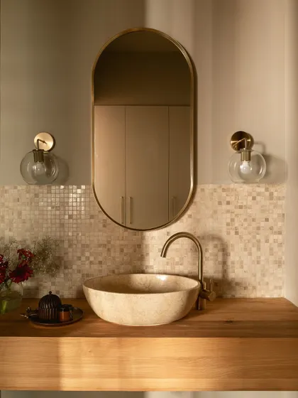 The powder room continues the home's earthy theme with a natural stone vessel sink, a wood countertop, and mother-of-pearl mosaic tiles. The warm lighting creates a moody and inviting atmosphere.