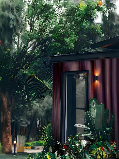 A close-up of a home with deep red WPC cladding, surrounded by lush greenery. This image captures the essence of efficient luxury, where high-end materials meet natural beauty.