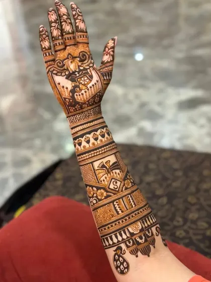This design tells a story with a bride and groom figure, a doli (palanquin), and personalized initials. It’s a beautiful way to capture wedding memories in your mehndi.