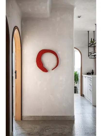 The name 'Unmei' was inspired by the Red Circle of Fate. This custom art piece abstracts that concept, and its texture blends perfectly with the lime-washed walls of the home, telling the clients' personal story.