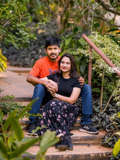 A relaxed and happy portrait of a couple sitting on garden steps. Their casual outfits and the natural setting create a very authentic and down-to-earth feel.