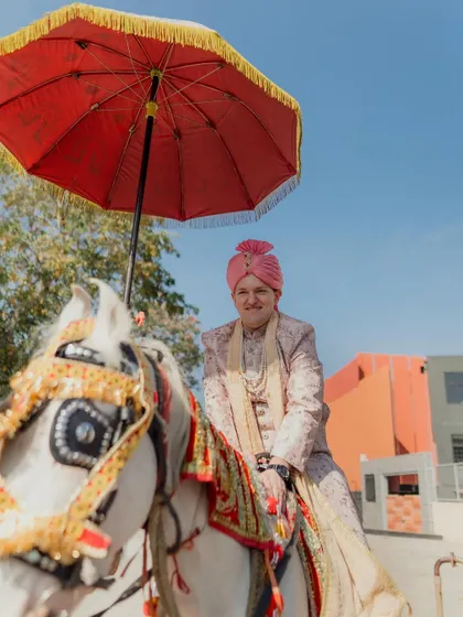 The groom's procession, or Baraat, is a joyous part of the wedding. Here, the groom arrives on a traditionally decorated horse, ready for the ceremony.