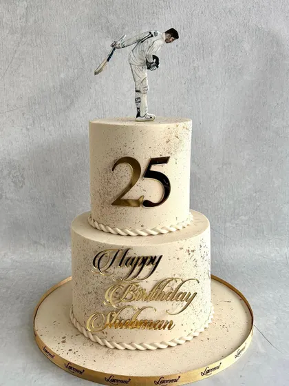 The full view of the elegant two-tiered cake we created for Shubman Gill's 25th birthday, featuring a speckled buttercream finish and gold accents.