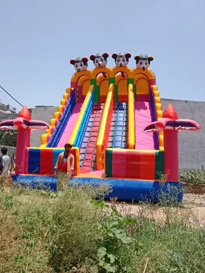 This is my giant Mickey Mouse themed inflatable slide, standing tall at 18x26 feet. The person standing next to it shows just how big and impressive it is, making it a guaranteed centerpiece for any large event or mela.