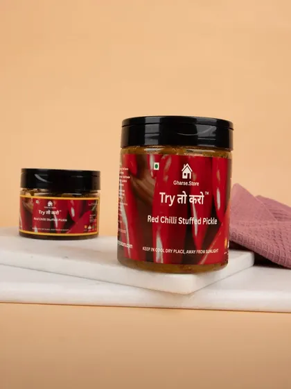 Jars of Red Chilli Stuffed Pickle presented on a marble slab, with simple styling to keep the focus on the product.