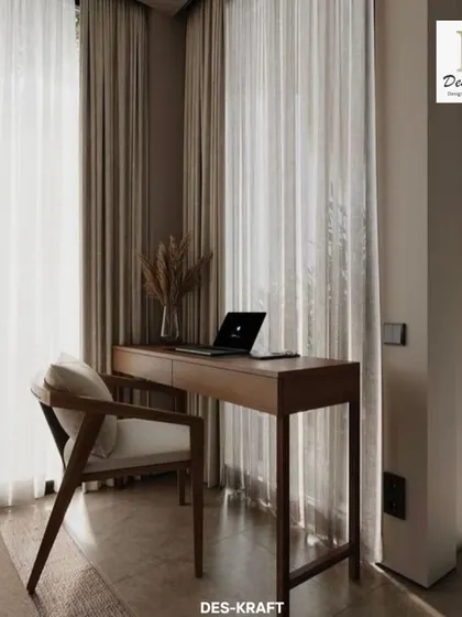 A simple yet elegant wooden desk and chair create a functional workspace by the window, bathed in natural light from the sheer curtains.