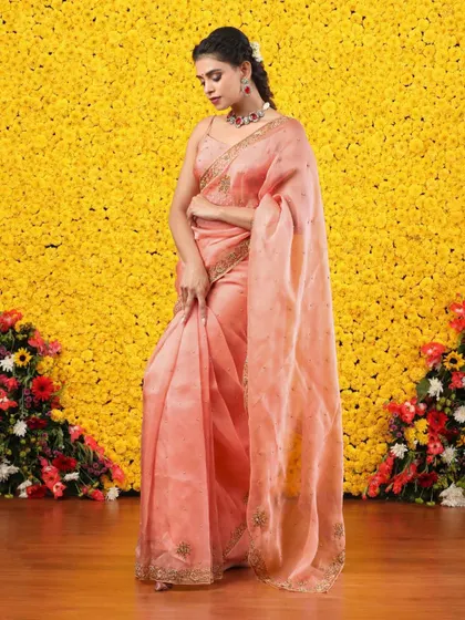 The full, standing view of the peach organza saree, a picture of sophistication and grace.