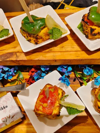 A beautifully arranged platter of our Stuffed Paneer Tikka appetizers. Each piece is individually plated and garnished with fresh mint and a wedge of lime, showcasing our attention to detail even for passed snacks.